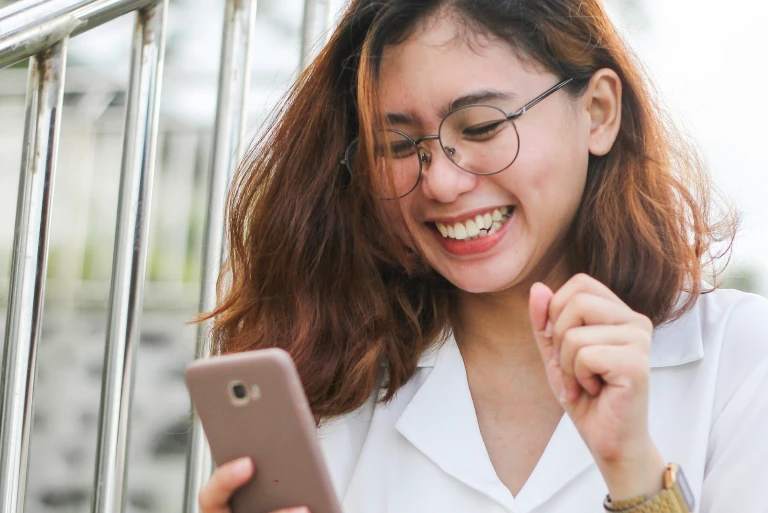 Girl looking at her phone in her hand, seeing content and smiling